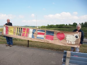 Ruth and Jon Aikens show the banner they made to welcome their daughter in HMCS KINGSTON.