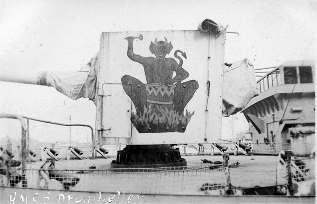 HMCS DRUMHELLER's gunshield art as designed by her ships company. Painted on the corvettes forward 4 inch gun, it depicts the devil beating on a fiery drum. The photo was taken in St. John's NF in 1943. Roger Litwiller Collection, courtesy Ross Milligan, RCNR. (RTL-REM173)