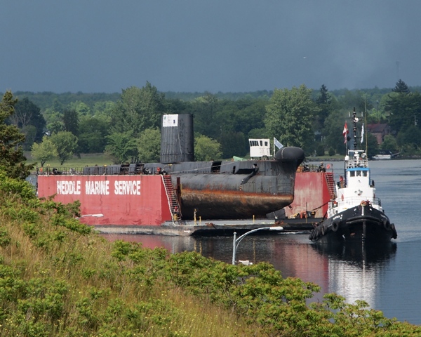 Former HMCS OJIBWA under tow in the St. Lawrence River approaching the seaway lock at Iroquois, Ontario on 3 June 2012. The cold war RCN submarine is being moved to Port Burwell, Ontario and will become a museum ship at the Museum of Naval History. Roger Litwiller Collection, courtesy Roger Litwiller. (RTL33769)